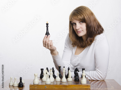 молодая девушка с фигурой королевы за шахматной доской
