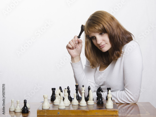 молодая девушка думает над очередным ходом в шахматы
