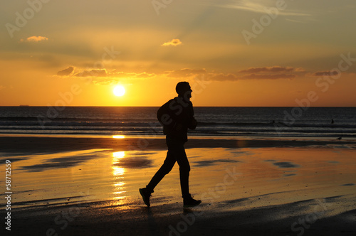 man running on the beach at sunset