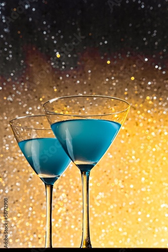 a pair of glasses of blue cocktail on table