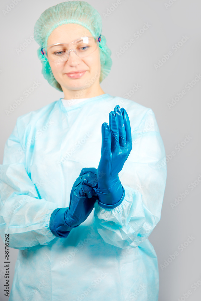 surgeon woman in sterile gown dresses sterile gloves Stock Photo