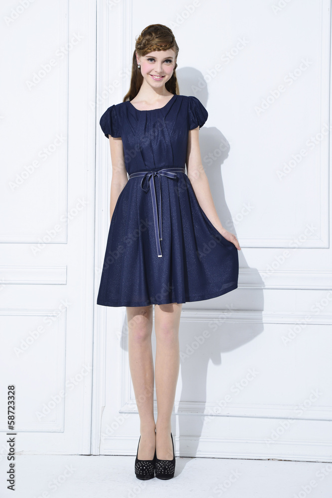 Portrait of beautiful young woman in black dress standing posing