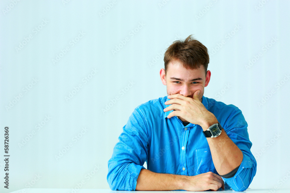 Portait of a young laughing businessman in blue shirt at office