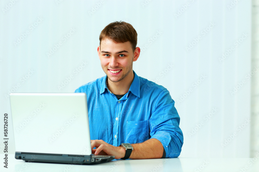 Young smiling businessman typing on the laptop Young smiling businessman typing on the laptop