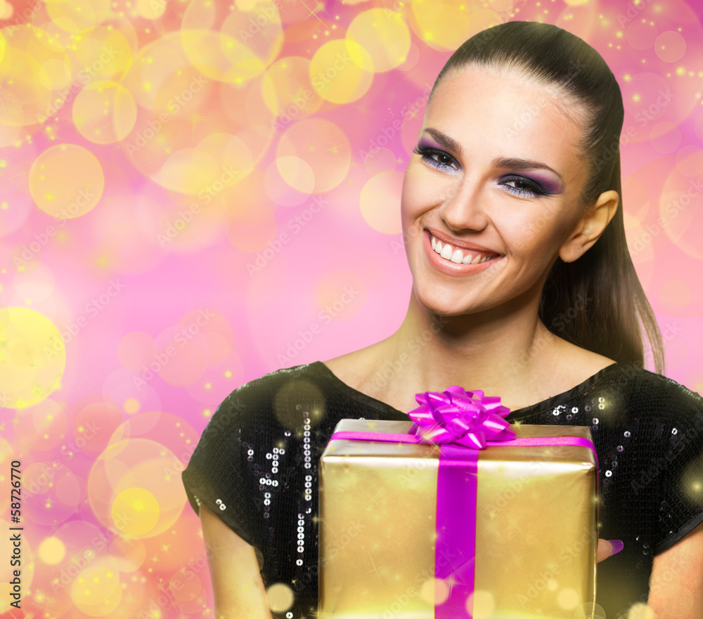 Beautiful woman holding a gift over a colorful shiny background Beautiful woman holding a gift over a colorful shiny background