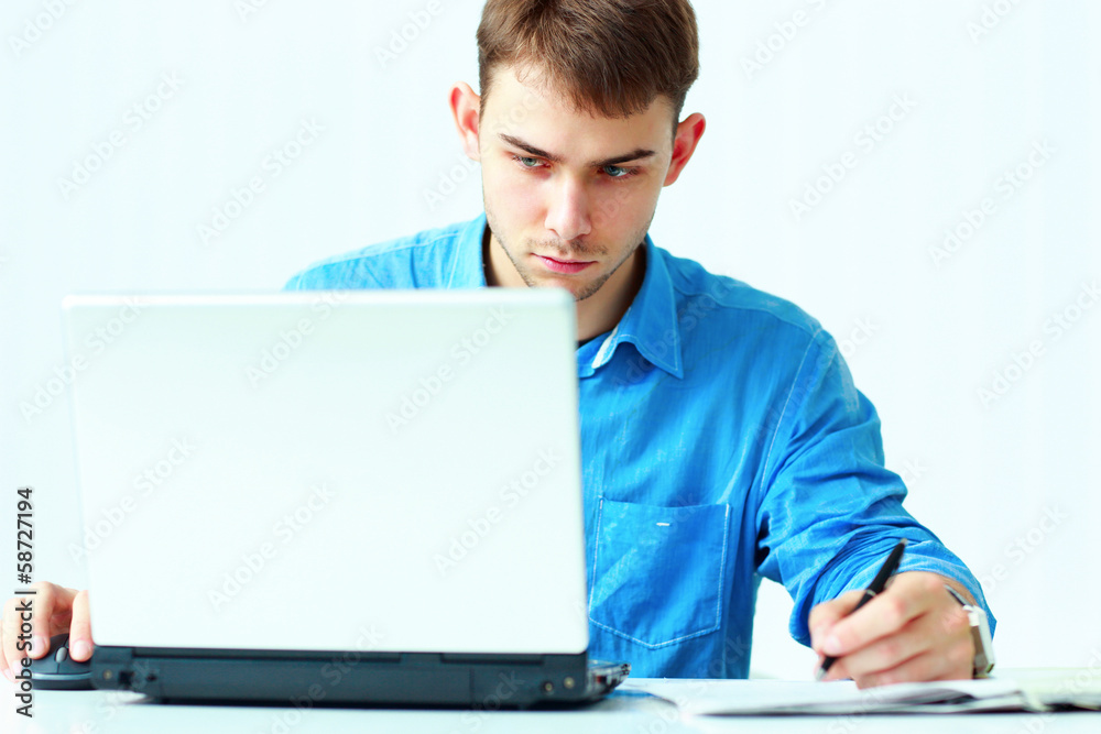 Young concentrated businessman writing notes down 