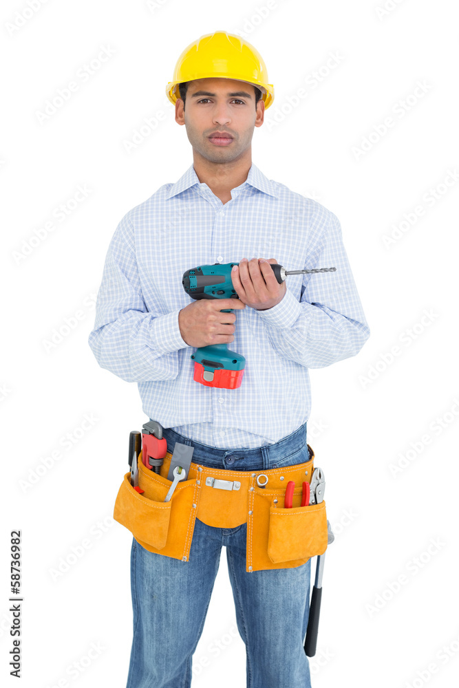 Serious handsome young handyman holding drill Serious handsome young handyman holding drill