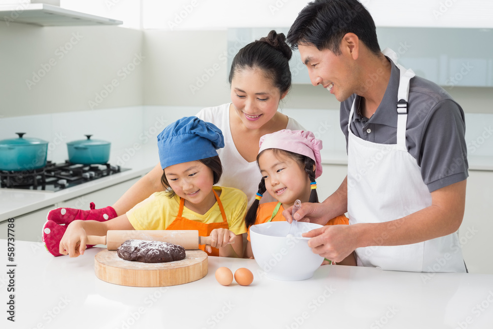 Happy family of four preparing cookies in kitchen