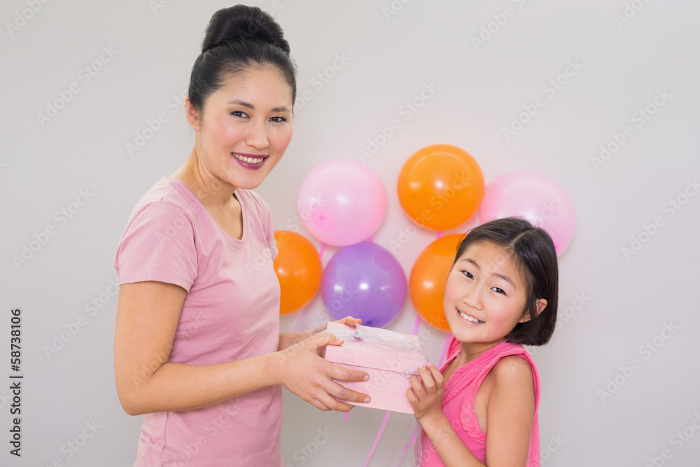 Woman giving gift box to a little girl at a birthday party Woman giving gift box to a little girl at a birthday party