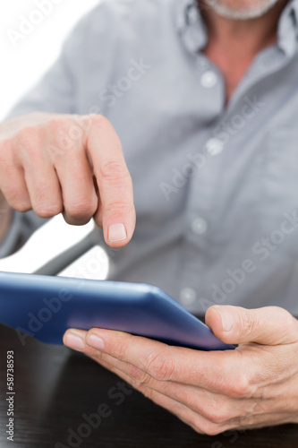 Mid section of a businessman using digital tablet at table