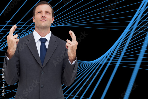 Composite image of serious businessman with fingers crossed is l photo