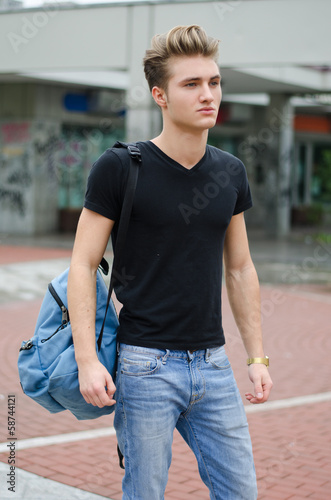 Attractive young man standing in city environment, with backsack photo