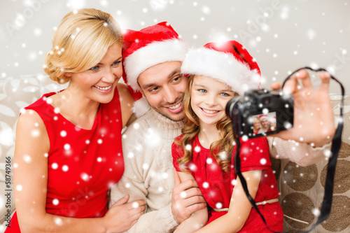 smiling family in santa helper hats taking picture