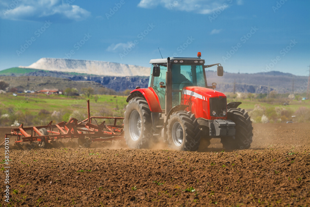 Fototapeta Brand new red tractor on the field working on land