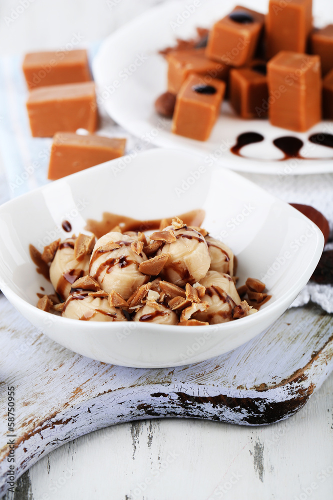 Many toffee on plate and in bowl on napkin on board close-up Many toffee on plate and in bowl on napkin on board close-up