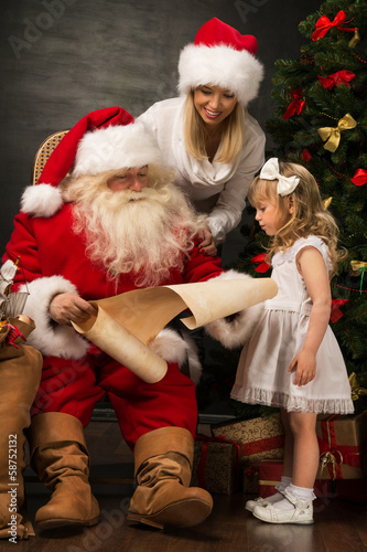 Santa Claus sitting at home with cute little girl and her mother