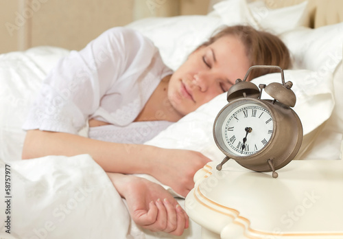 sleeping woman resting in bed with alarm clock