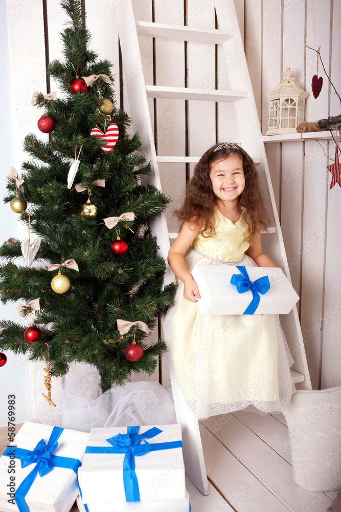 Happy smiling kid holding gifts near Christmas tree. Happy smiling kid holding gifts near Christmas tree.