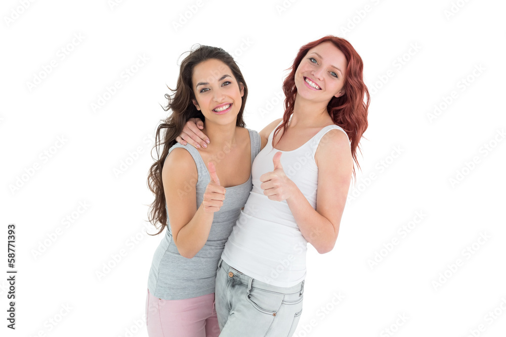 Portrait of two young female friends gesturing thumbs up Portrait of two young female friends gesturing thumbs up