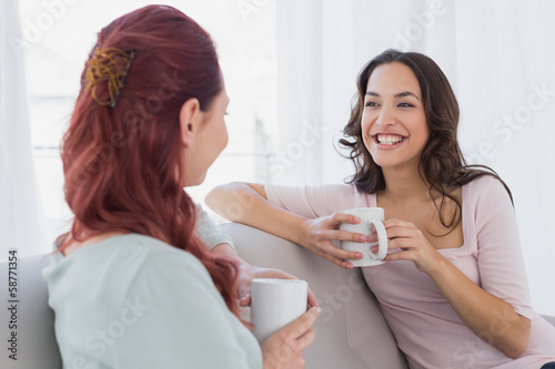 Female friends enjoying a chat with coffee cups at home