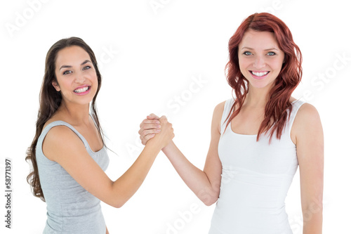 Two cheerful young female friends arm wrestling