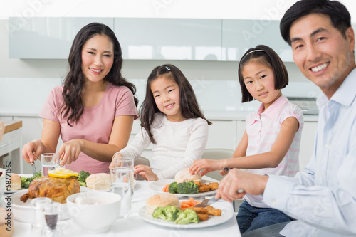 Happy family of four enjoying healthy meal in kitchen