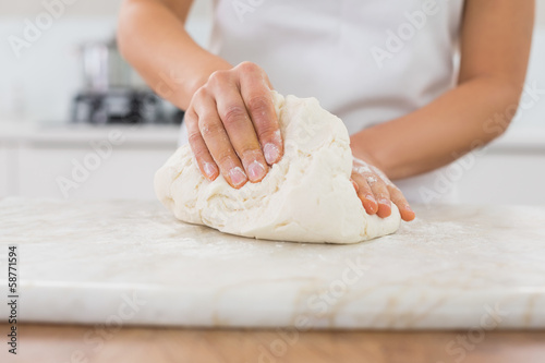 Tableau sur toile Mid section of a woman kneading dough in kitchen