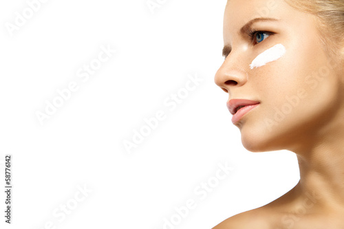 Woman applying moisturizer cream on face isolated