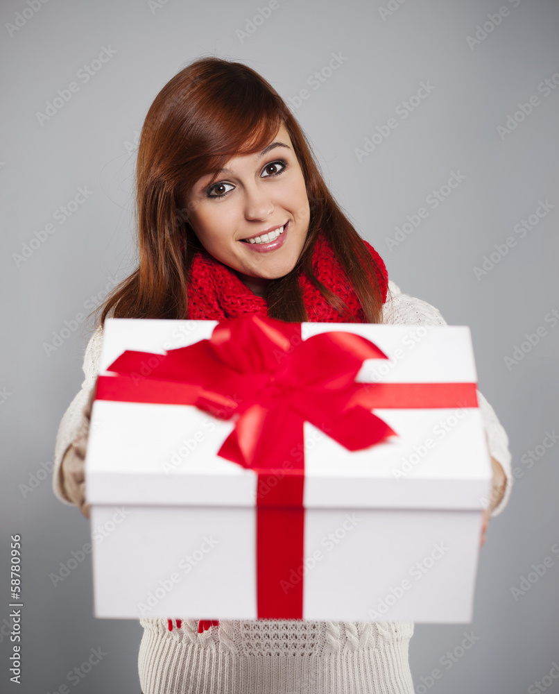 Brunette young woman giving white christmas gift with red ribbon Brunette young woman giving white christmas gift with red ribbon