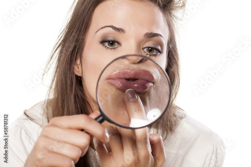 young woman checks her lips through the magnifying glass photo