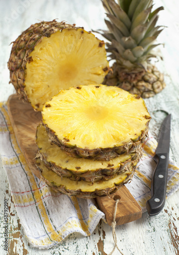 Pineapple with slices on wooden cooking board