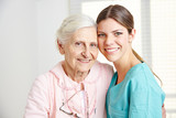 Caregiver embracing happy senior woman