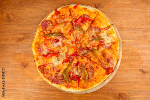 Tasty pepperoni pizza on wooden board on wooden background