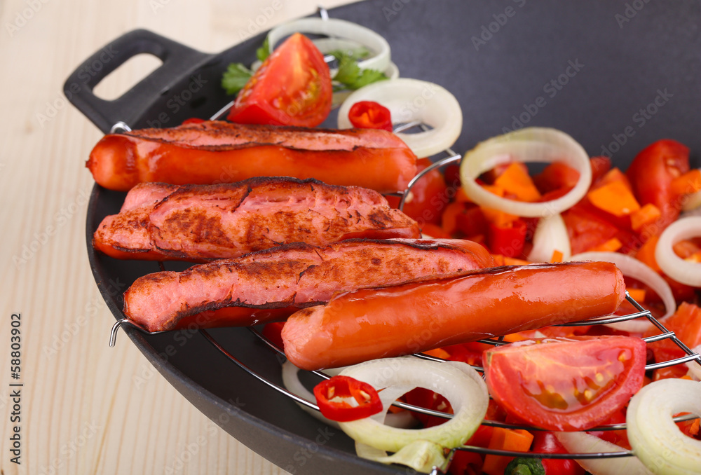 Delicious sausages with vegetables in wok Delicious sausages with vegetables in wok