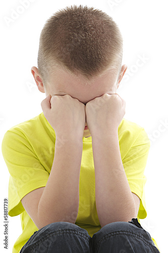 sad lonely little boy covering his face with his hands photo