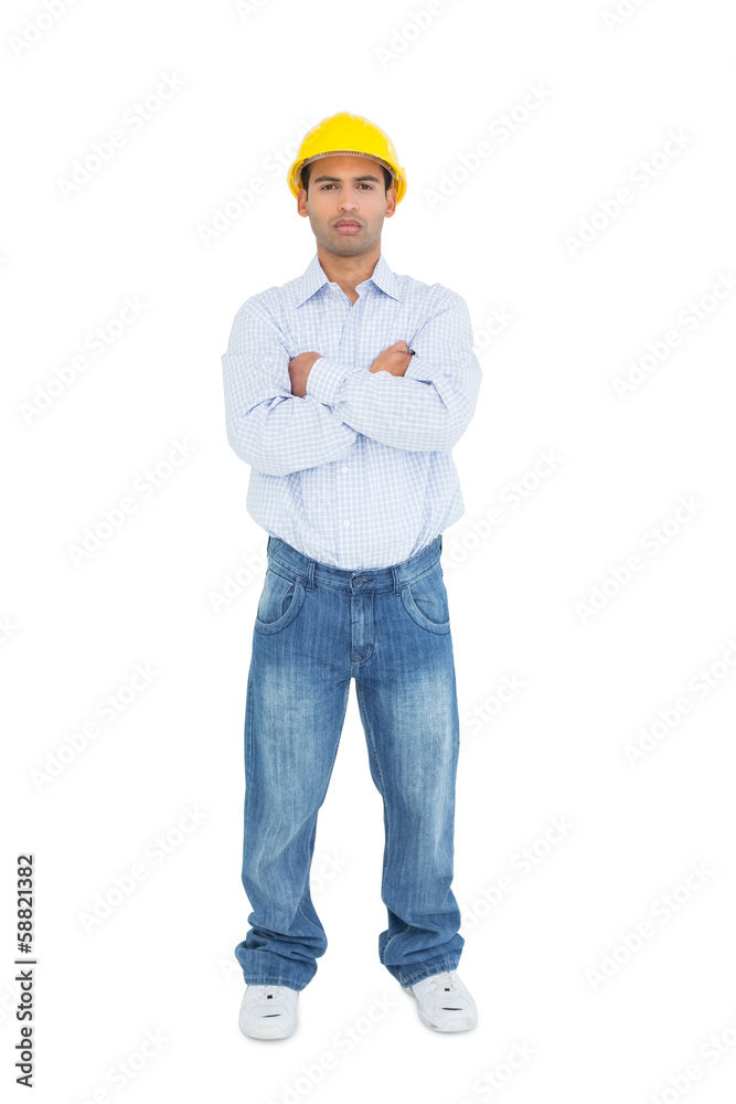 Full length of a serious handyman wearing a yellow hard hat Full length of a serious handyman wearing a yellow hard hat