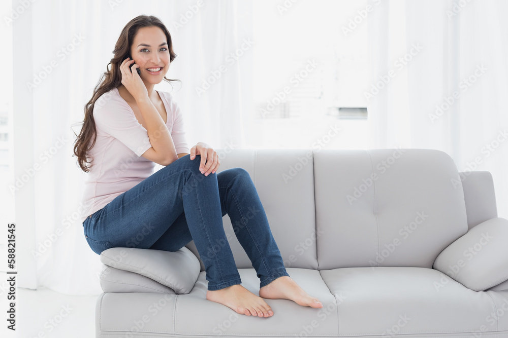 Relaxed young woman using cellphone on sofa at home Relaxed young woman using cellphone on sofa at home