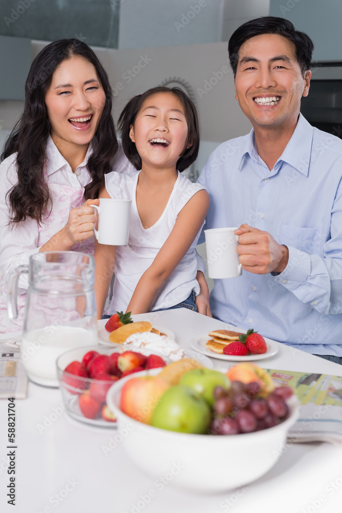 Cheerful young girl enjoying breakfast with parents