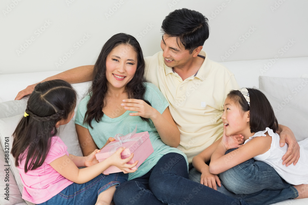 Family presenting mother with a gift box in living room