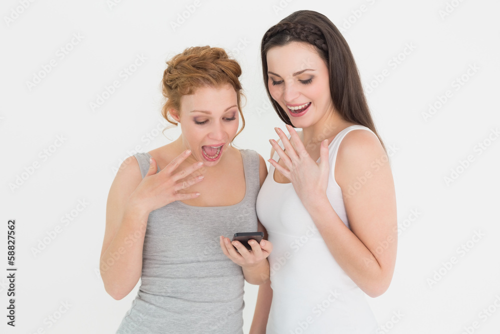 Two cheerful friends looking at mobile phone Two cheerful friends looking at mobile phone