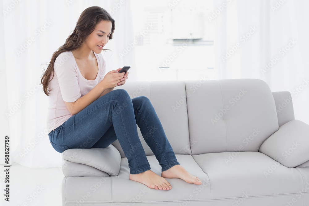 Relaxed woman text messaging on sofa at home