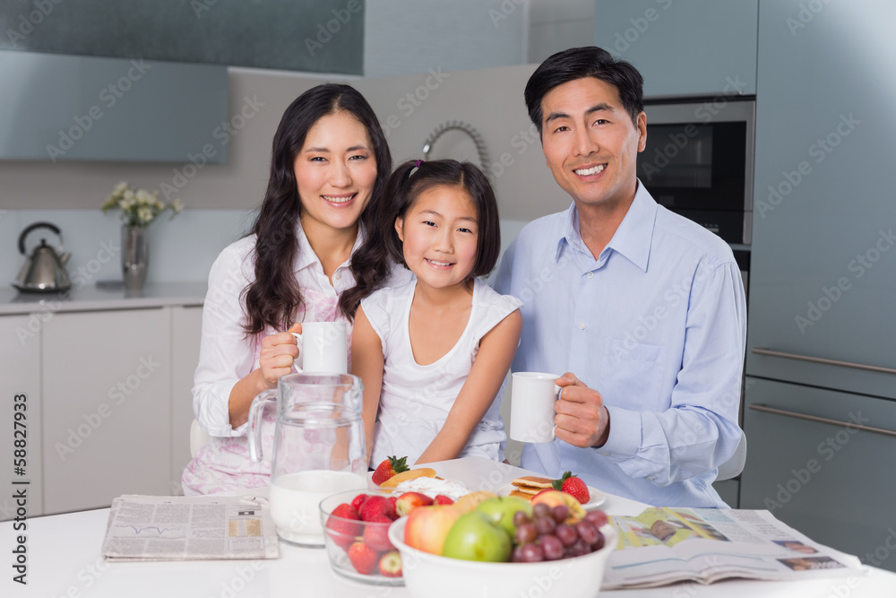 Happy young girl enjoying breakfast with parents