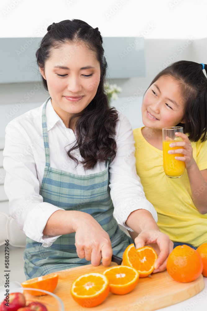 Woman with her young daughter cutting fruit in kitchen Woman with her young daughter cutting fruit in kitchen