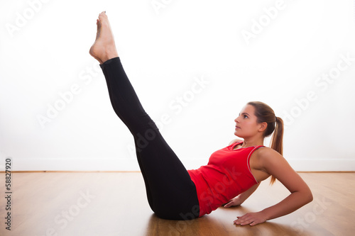 Cuadro en lienzo Young woman exercising - stretching legs in the air
