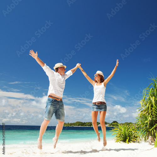 Happy couple jumping on the tropical beach