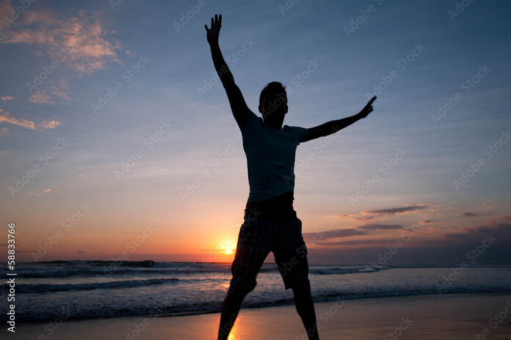 Man jumping on the beach at sunset