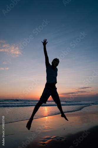 Man jumping on the beach at the sunset