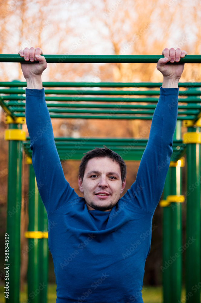 Obraz premium Athletic man doing pull-up on horizontal bar