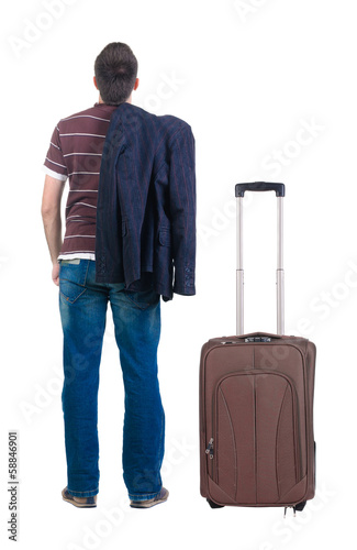 young man traveling with suitcas  looks ahead. rear view.