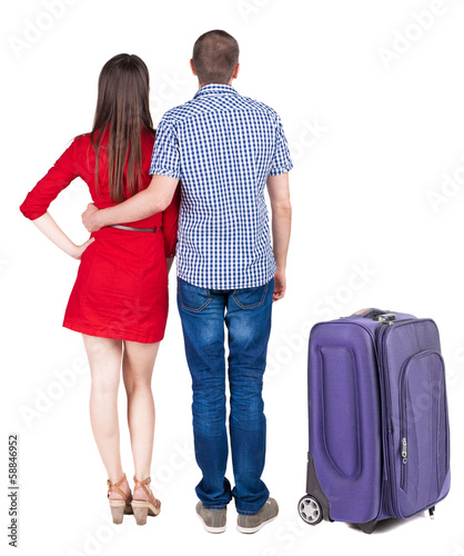 Back view of young couple traveling with suitcas .